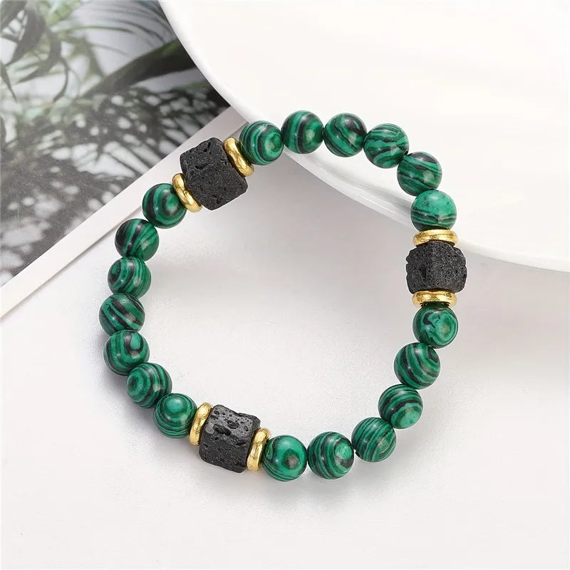 Green beaded bracelet with black and gold accents on a white surface