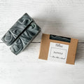 Two bars of soap and a box labeled 'Dapper' on a light wooden surface.
