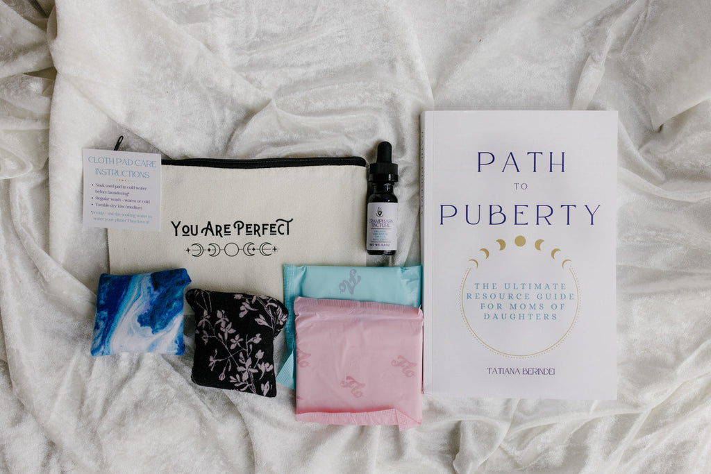 Product set including a book titled 'Path to Puberty', pouch, and other items on a textured surface. with cramp bark tincture