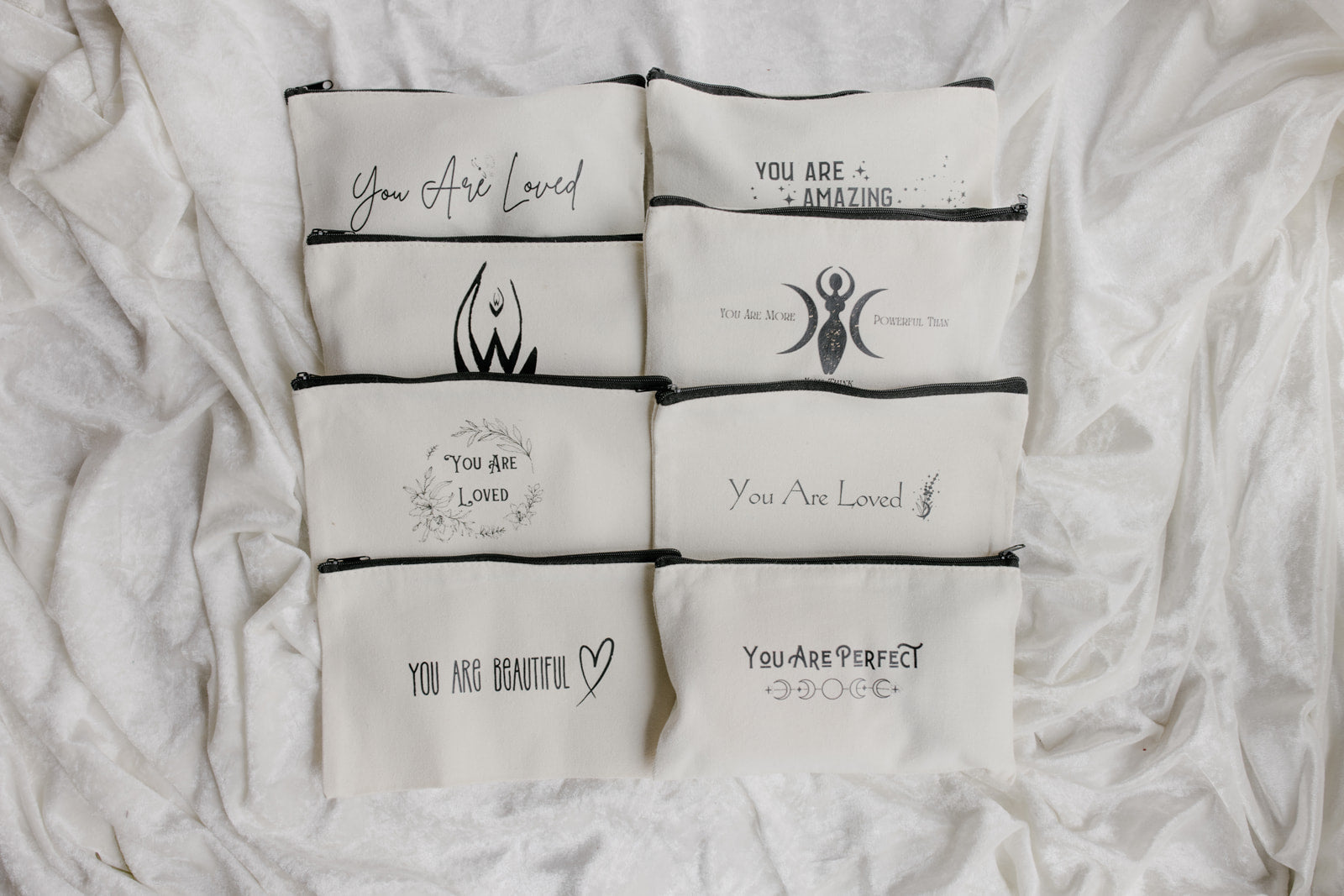 Set of white pouches with motivational text on a white fabric background