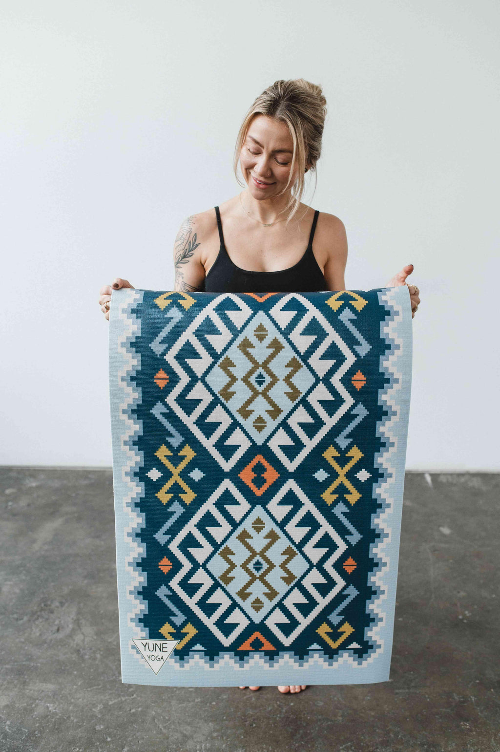 Woman holding a large decorative rug with geometric pattern